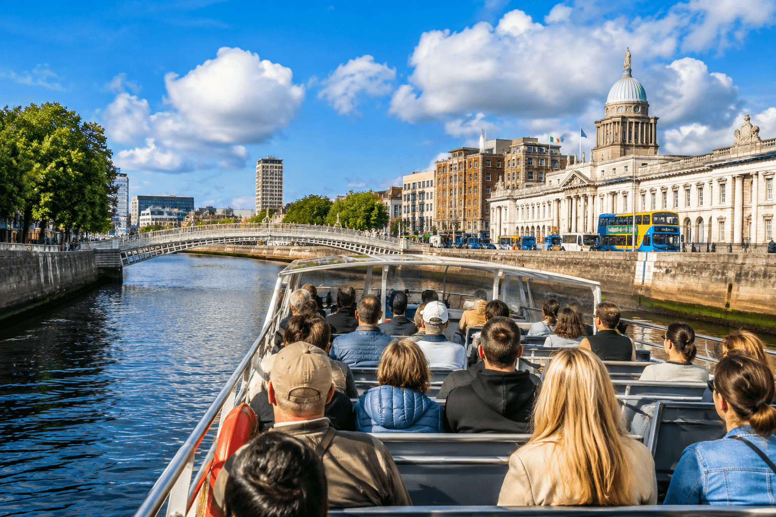 Passengers on a Dublin boat tour cruising along the River Liffey with views of the Custom House and city waterfront.